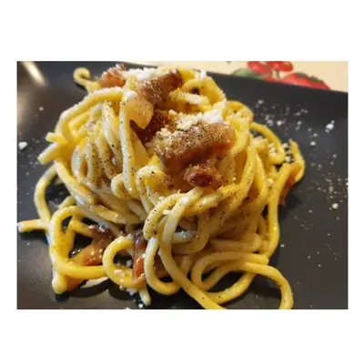 a pile of pasta sitting on a black plate at House 5 minutes walk from Vatican Museums in Rome