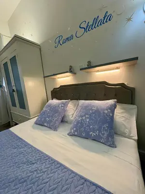 a bed with two pillows and a sign on the wall at Roma Stellata in Rome