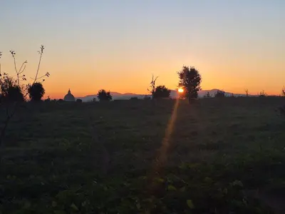 a sunset in a field with the sun setting at Il Pineto in Rome