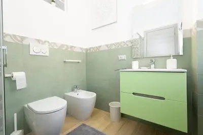 a green bathroom with a toilet and a sink at Casa Libetta in Rome