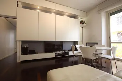 a living room with white cabinets and a table and chairs at Cipro 2BR Holiday House in Rome