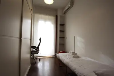 a room with a bed and a chair and a window at Cipro 2BR Holiday House in Rome