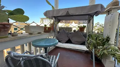 a bed on a balcony with a table and a chair at The attic in Rome