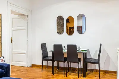 a dining room table with black chairs and a mirror at Giulia Apartment in Rome