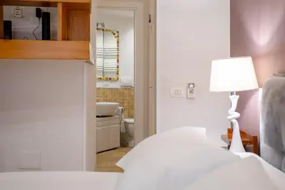 a bedroom with a bed and a lamp and a bathroom at Oliviero - Colosseo Apartment with Terrace in Rome