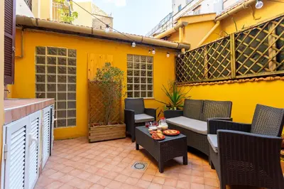 a patio with chairs and a table on a yellow wall at Oliviero - Colosseo Apartment with Terrace in Rome