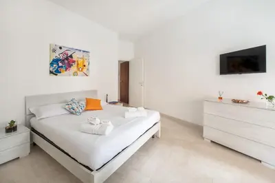 a white bedroom with a bed and a tv at Lacasadigió in Rome