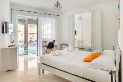 a white bedroom with a large bed and a balcony at Lacasadigió in Rome