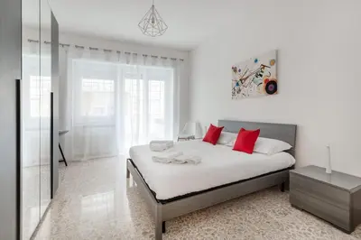 a white bedroom with a bed with red pillows at Lacasadigió in Rome