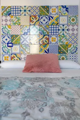 a bed with a red pillow and a wall with tiles at Center Suite Garbatella in Rome