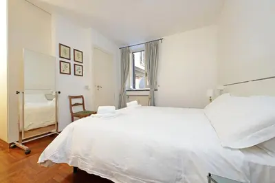 a white bedroom with a large bed and a chair at Pantheon Apartment Rondanini in Rome