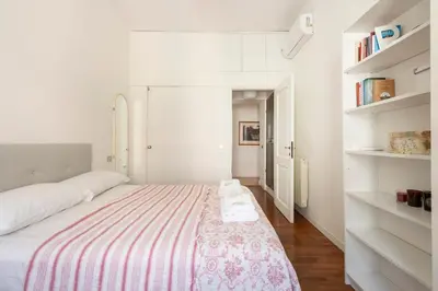 a white bedroom with a large bed and shelves at Trastevere Penthouse in Rome