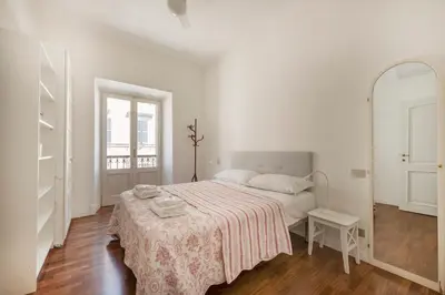 a white bedroom with a bed with a pink blanket at Trastevere Penthouse in Rome