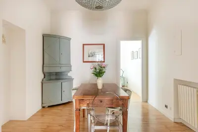 a dining room with a table with a vase of flowers on it at Trastevere Penthouse in Rome