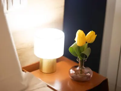 a table with a lamp and a vase with yellow flowers at BNB Ostiense in Rome