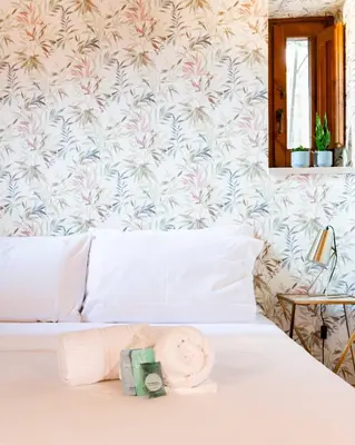 a bedroom with a white bed with a flowery wallpaper at ZENO 13 Paradiso - Casa Verde in Rome