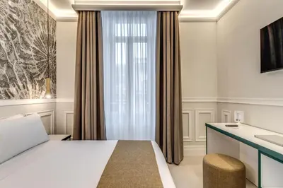 a bedroom with a bed and a desk and a window at Relais Marco Polo in Rome