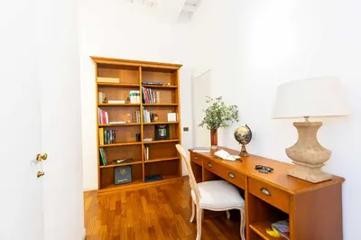 an office with a desk with a lamp and a book shelf at Luxury House Lungaretta - ZENO 50 in Rome