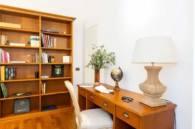 an office with a desk with a lamp and a book shelf at Luxury House Lungaretta - ZENO 50 in Rome