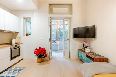 a living room with a kitchen and a tv on the wall at Welcome to Retreat in Trastevere in Rome