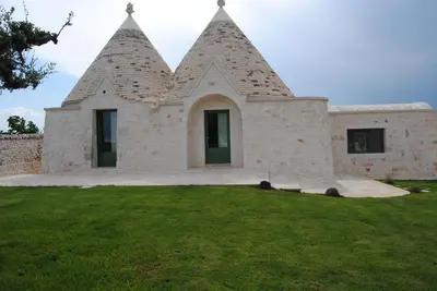 a building with two towers on top of a grass field at Trullo Amato with exclusive pool in Rome