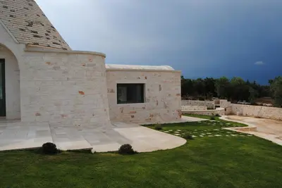 a stone house with a grass yard and a building at Trullo Amato with exclusive pool in Rome