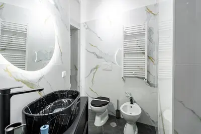 a bathroom with a sink and a toilet and a mirror at Centocinque Aparthouse - Luxe in Rome
