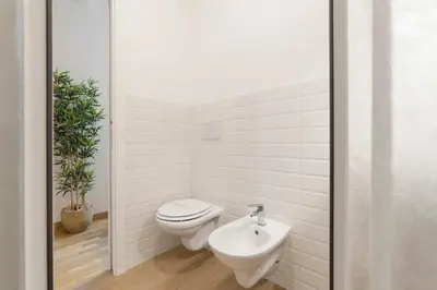 a white bathroom with a toilet and a sink at CS Central Station Termini Monti Apartment in Rome