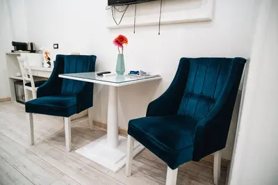 a table with two blue chairs and a vase with a flower at Escape Suite Guest House - Ca Domus Collection in Rome