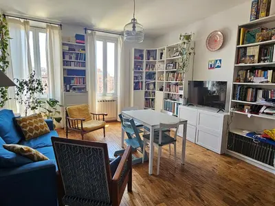 a living room with a table and chairs and bookshelves at Luminoso attico con terrazza in Rome