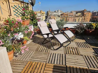 two chairs sitting on a balcony with flowers at Luminoso attico con terrazza in Rome