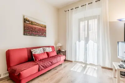 a red couch in a living room with a window at Elegant flat in front of Vatican museum in Rome