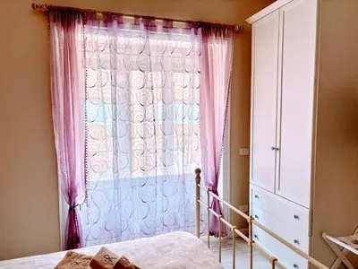 a bedroom with a window with pink curtains and a bed at Appartamento Aurelio in Rome