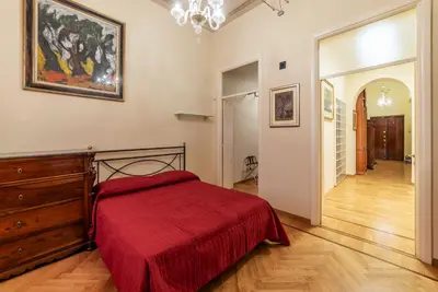 a bedroom with a red bed and a painting on the wall at GuestHost - Historic Apartment in Sallustiano in Rome