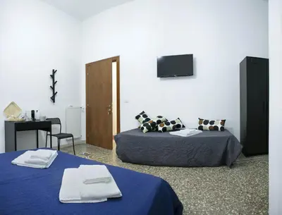 two beds in a room with a tv on the wall at Lorenzo's Rooms in Vatican in Rome