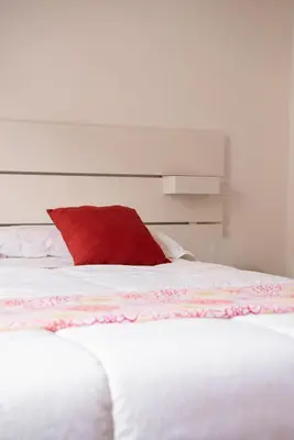 a red pillow sitting on top of a white bed at The Vatican Rest, Elegant Apt Nerby the Basilica in Rome