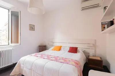 a white bedroom with a bed with colorful pillows at The Vatican Rest, Elegant Apt Nerby the Basilica in Rome