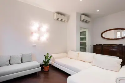 a living room with two white couches and a mirror at The Vatican Rest, Elegant Apt Nerby the Basilica in Rome