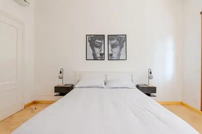 a white bed in a white bedroom with two lamps at Casa Maddalena luxury appartment in Rome