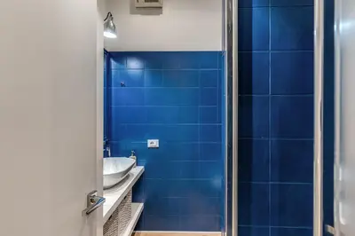 a blue tiled bathroom with a sink and a mirror at Residenza Margherita in Rome