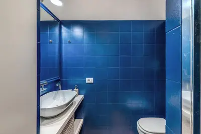 a blue tiled bathroom with a sink and a toilet at Residenza Margherita in Rome