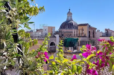 a view of a building with pink flowers in the foreground at Colosseo Attico Particolare Terrazza Panoramica in Rome