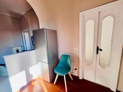 a green chair in a room with a refrigerator at Fast Re Apartment in Rome