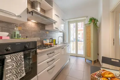 a kitchen with white cabinets and a stove top oven at Gemelli Apartment in Rome