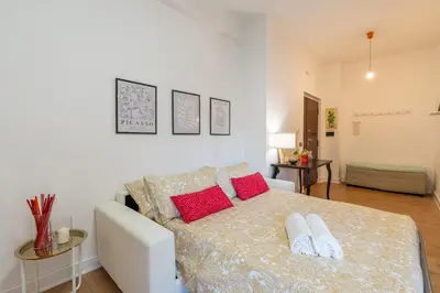 a white bedroom with a bed with red pillows at Gemelli Apartment in Rome