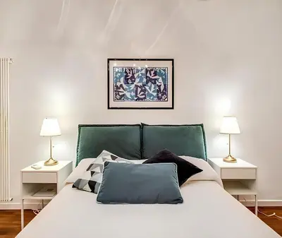 a white bed with a green headboard and two lamps at Casa Roma in Rome