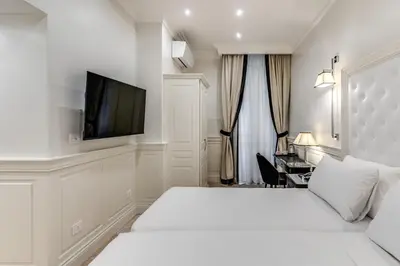 a white bedroom with a bed and a desk at ACA Hotel Viminale in Rome
