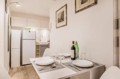 a white kitchen with a table with wine glasses and a refrigerator at Vatican Chic House II in Rome