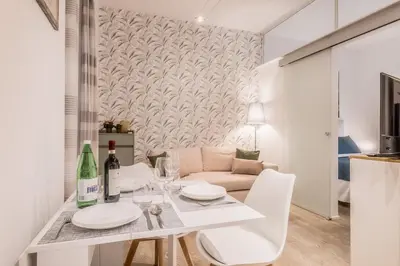 a white dining room with a table and a couch at Vatican Chic House II in Rome