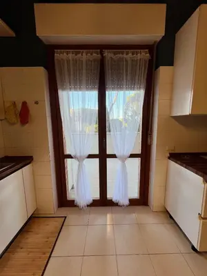 a kitchen with a window with white curtains at The BestaHouse in Rome